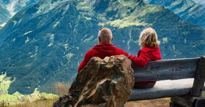 Couple sitting on bench on mountain ledge
